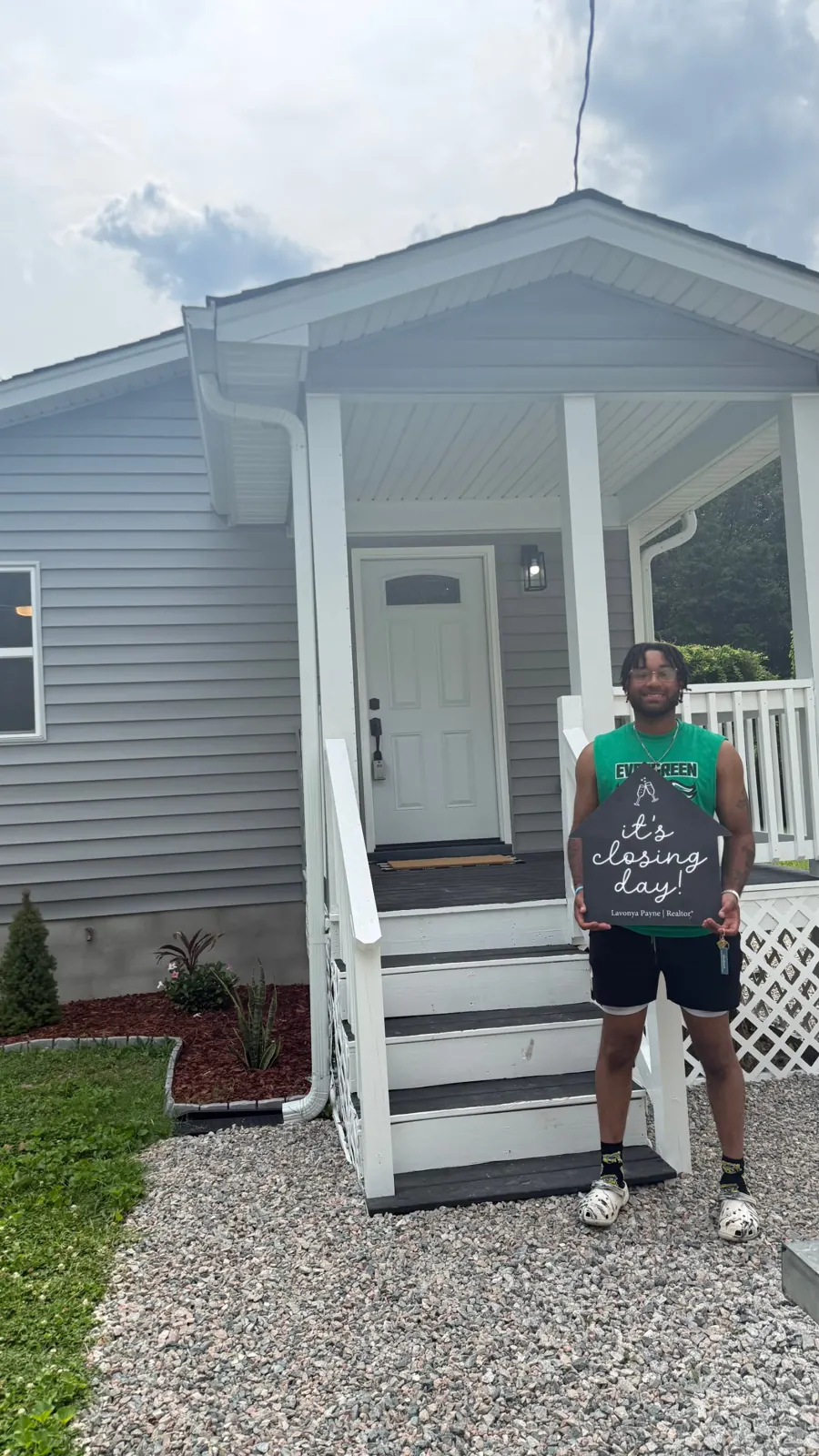 First-time buyer holding an It's Closing Day sign outside his new home near Petersburg VA