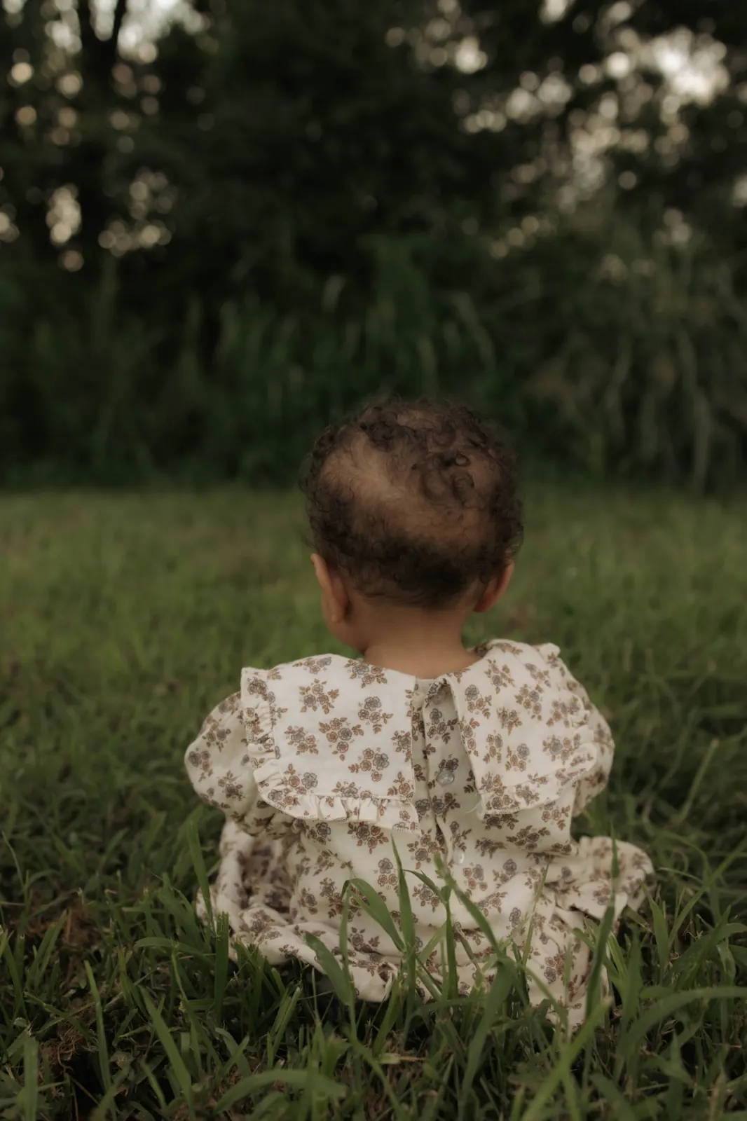 Lavonya's daughter sitting in the grass in a floral dress