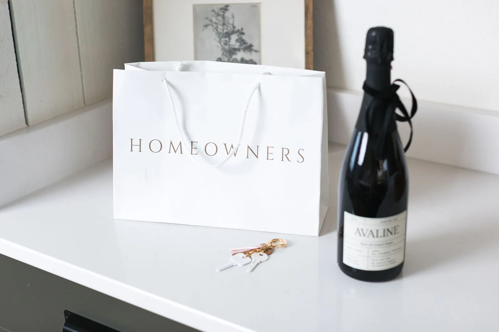Homeowners gift bag, champagne, and new keys on a kitchen counter
