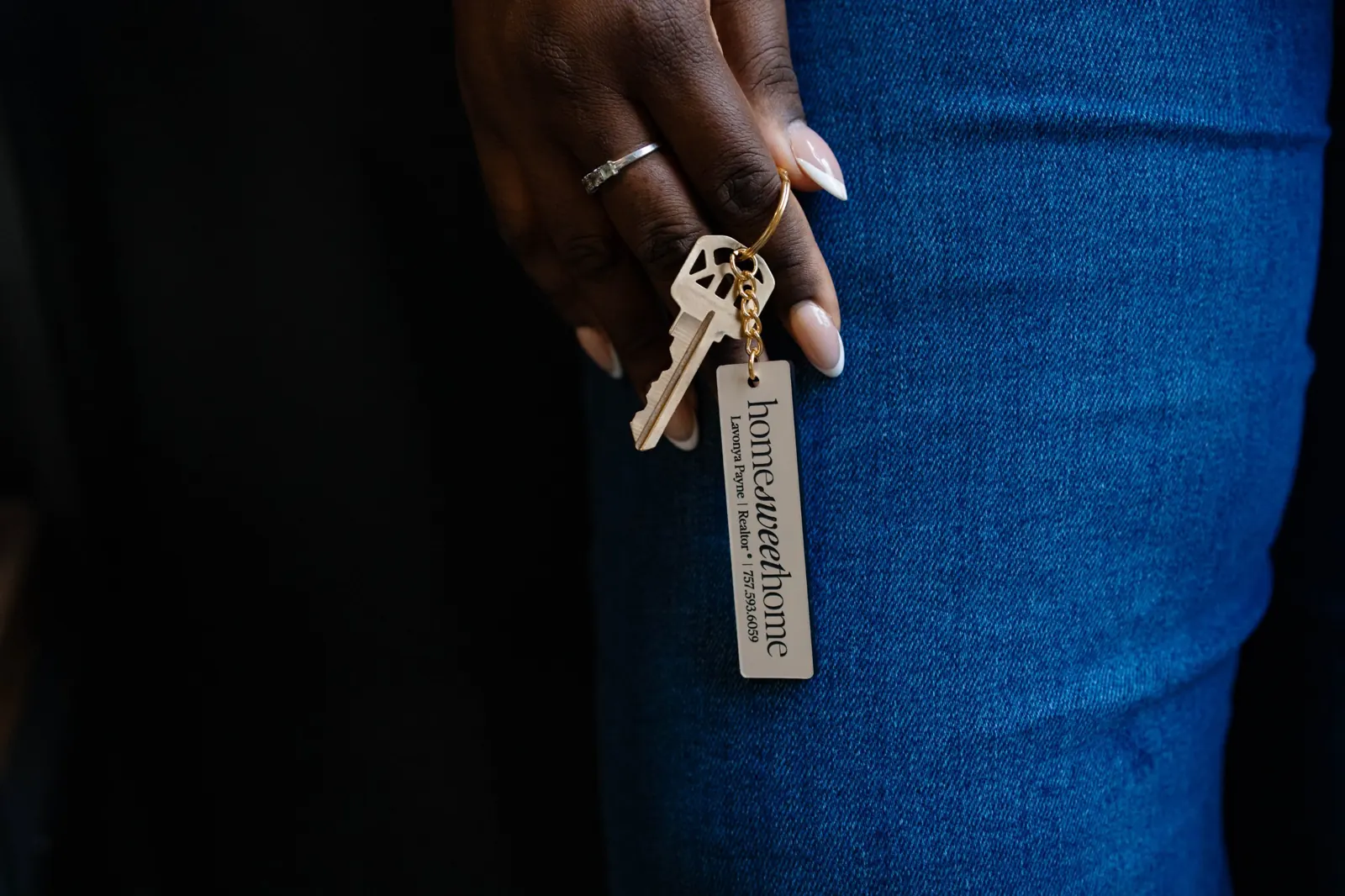 Hand holding a house key on a Lavonya Payne Realtor keychain