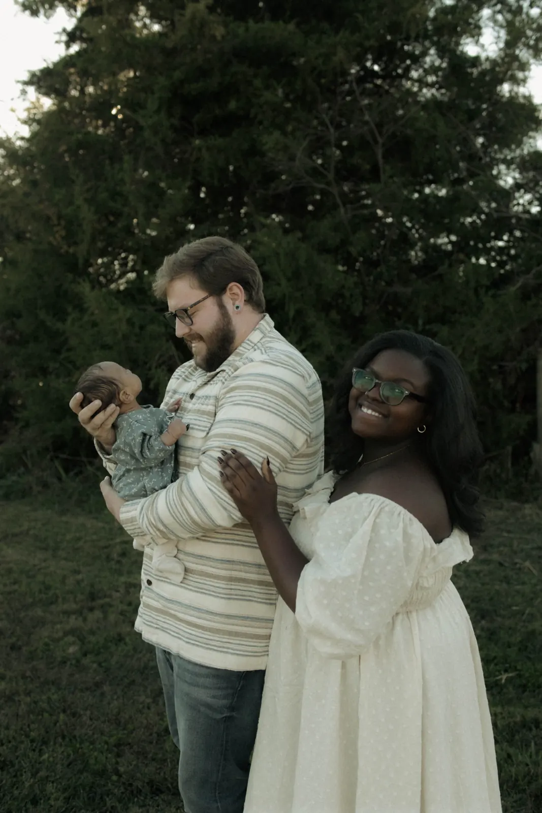 Lavonya smiling outdoors with her family and newborn