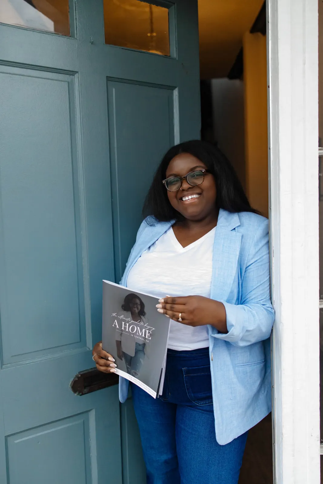Lavonya Payne smiling in a doorway holding her Central Virginia home buyer guide